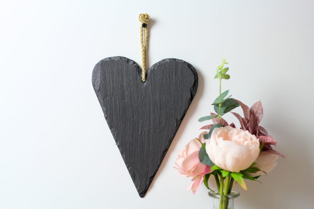 Welsh slate heart hanging on a wall with hemp rope.