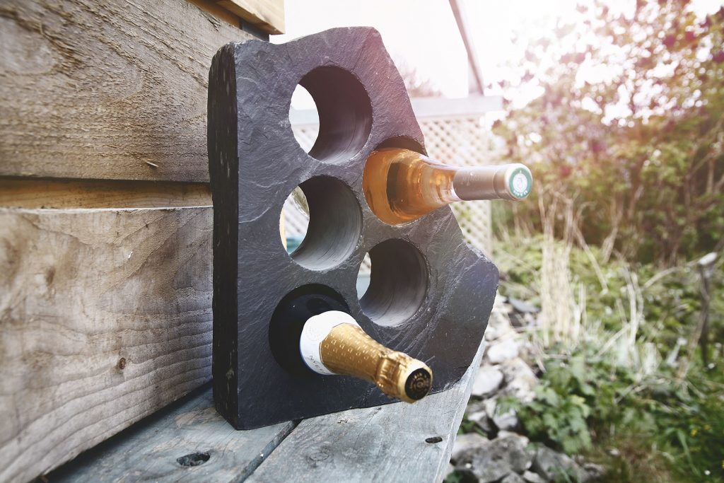 Blue grey Welsh slate wine rack with two bottles of wine glistening in the sunshine