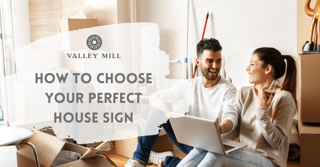 couple smiling together whilst designing a house sign on their laptop