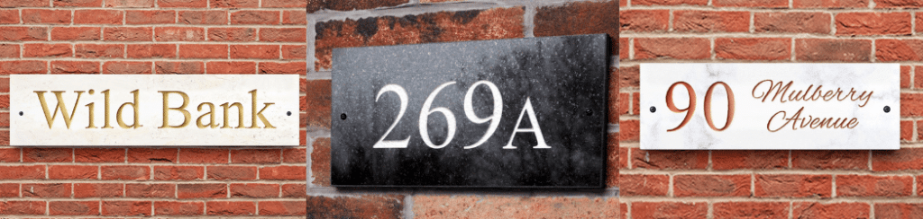 white limestone house sign and next to it a black granite house sign and next to that a white marble house sign